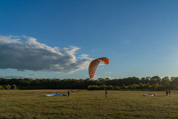 Learn to paraglider, paraglider catching wind flow from the ground in summer warm weather with blue...