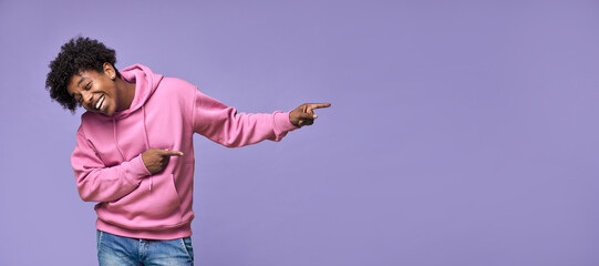 Happy funny African American teen guy pointing fingers aside advertising new promo offer. Smiling...