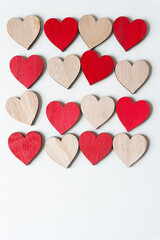 array of plain and painted red wooden hearts on blank paper