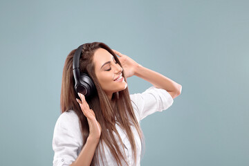 Portrait of a happy girl listening music with wireless headphones from a smartphone. Girl uses...
