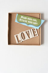 rub em on, stick em up! and the word "love" inside a shallow cardboard box and isolated on plain paper
