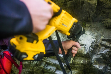Drilling holes in rock in order to bolt in anchors for rappel station.