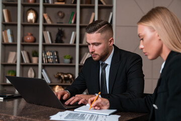 Businesswoman and businessman wearing formal wear sitting workin