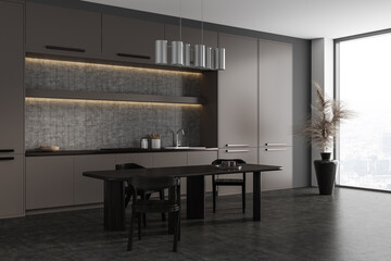 Dark kitchen interior with cooking area and dining table, panoramic window
