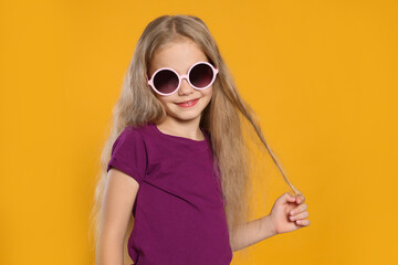 Fototapeta premium Girl in stylish sunglasses on orange background