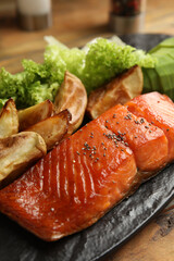 Tasty cooked salmon and vegetables served on wooden table, closeup. Healthy meals from air fryer