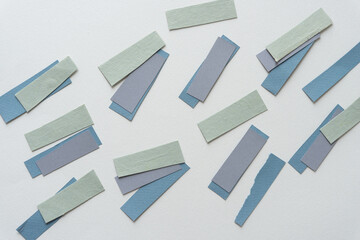 short paper stripes in green, gray, and blue on blank paper