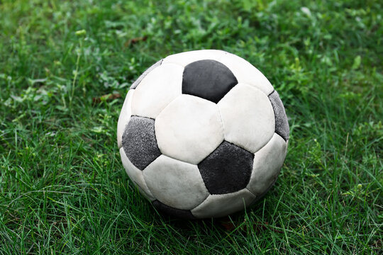 Dirty soccer ball on fresh green grass outdoors, closeup