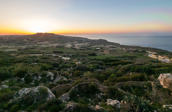 Sunset view of the coast of Gozo, Malta taken from Zebbug at sunset with orange and purple sky