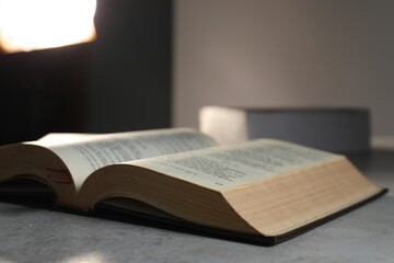Fototapeta premium Closeup view of open hardcover Bible on grey table indoors, space for text. Religious book