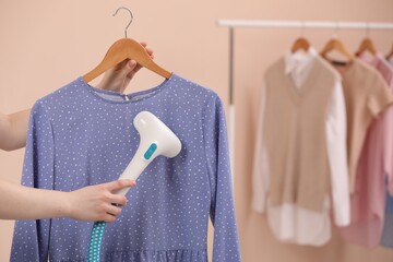 Woman steaming blouse on hanger at home, closeup. Space for text - obrazy, fototapety, plakaty