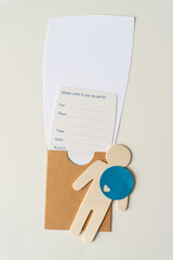 wooden stick figure silhouette cutout, circle with heart, brown cardboard pocket envelope, invitation card with text and blank space for your unique copy