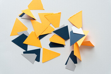 somewhat triangular paper shapes in orange-yellow, blue and white on blank paper