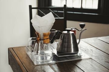 Coffee maker, grinder and kettle on wooden table in cafe