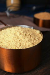 Saucepan with mustard powder on wooden table, closeup