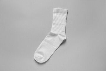 One white sock on light grey background, top view