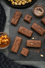 Delicious chocolate candy bars with caramel and nuts on grey table, flat lay