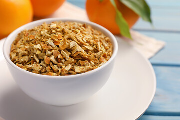 Bowl of dried orange zest seasoning and fresh fruits on blue wooden table