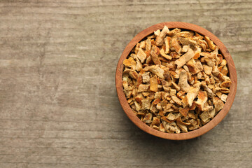 Bowl of dried orange zest seasoning on wooden table, top view. Space for text