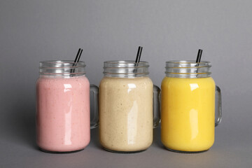 Mason jars with different smoothies on grey background