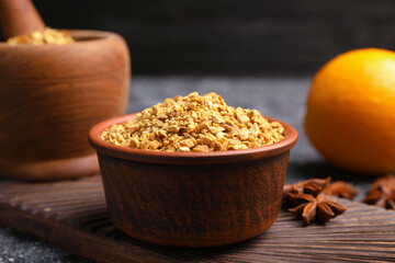 Bowl of dried orange zest seasoning, fresh fruit and anise on grey table