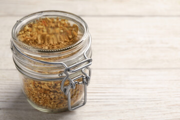 Jar of dried orange zest seasoning on white wooden table. Space for text