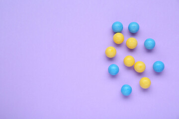 Many bright chewy gumballs on lilac background, flat lay. Space for text