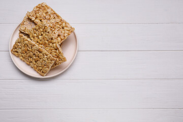 Delicious peanut bars (kozinaki) on white wooden table, top view. Space for text