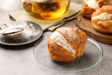 Delicious profiteroles filled with cream on grey table, space for text
