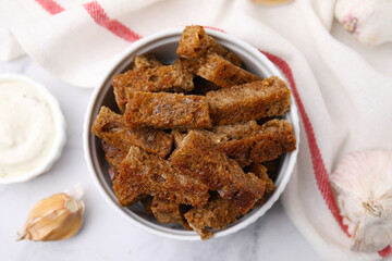 Crispy rusks with sauce on white marble table, flat lay