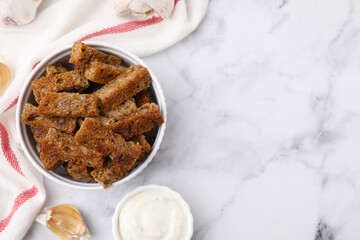 Crispy rusks with sauce on white marble table, flat lay. Space for text