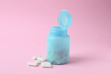 Jar with chewing gums on pink background
