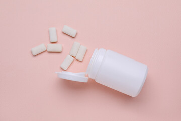 Jar with chewing gums on light pink background, flat lay