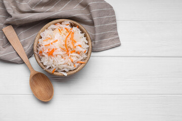 Bowl of tasty sauerkraut on white wooden table, flat lay. Space for text