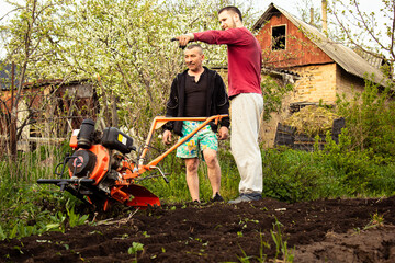 Planting vegetables under the walk-behind tractor. A man with a walk-behind tractor in the garden....