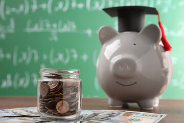 Scholarship concept. Glass jar with coins, piggy bank, graduation cap and dollar banknotes on...