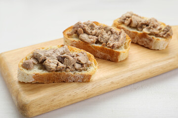 Tasty sandwiches with cod liver on white wooden table