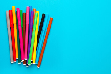 Many bright markers on light blue background, flat lay. Space for text