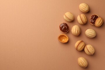 Homemade walnut shaped cookies with boiled condensed milk on pale brown background, flat lay. Space for text