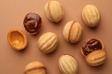 Homemade walnut shaped cookies with boiled condensed milk on pale brown background, flat lay