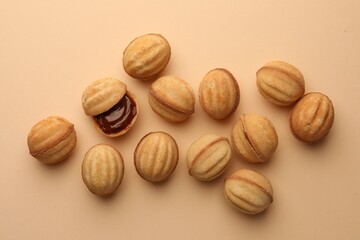 Homemade walnut shaped cookies with boiled condensed milk on beige background, flat lay