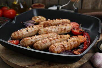 Tasty grilled sausages with vegetables on wooden table, closeup