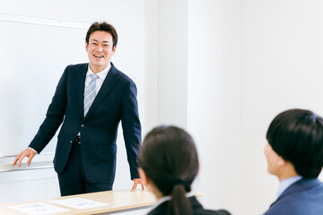 会議室・教室で楽しい研修・塾・講義・講習・セミナーをする笑顔の男性（楽しい・面白い・冗談・ジョーク）
