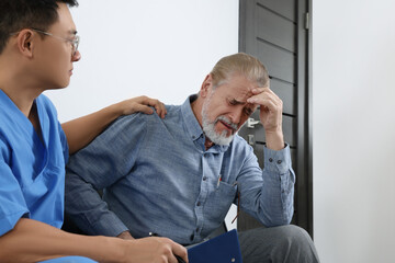 Doctor with clipboard consulting senior patient in clinic