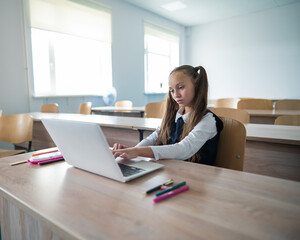 Caucasian girl studying on a laptop in a classroom. 