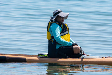 Woman sail on a SUP boards with special seating chair and wet suit and life jacket for paddling....