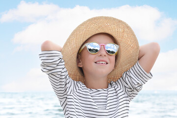 Little girl wearing sunglasses and hat at beach on sunny day