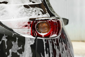 Auto with cleaning foam at car wash, closeup