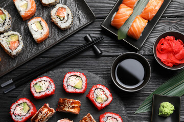Flat lay composition with different sushi rolls on black wooden table