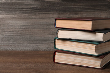 Stack of old hardcover books on wooden table, space for text